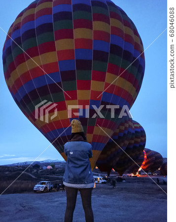 Young woman watching hot air balloons at early morning with rocky landscape in Cappadocia, Turkey 68046088