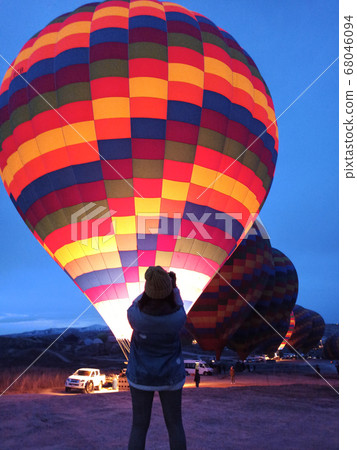 Young woman watching hot air balloons at early morning with rocky landscape in Cappadocia, Turkey Young woman watching hot air balloons at early morning with rocky landscape in Cappadocia, Turkey 68046094