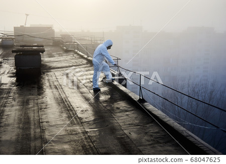 Worker scientist wearing protective coverall and gas mask doing ecological tests on the roof Worker scientist wearing protective coverall and gas mask doing ecological tests on the roof 68047625