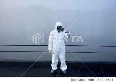 Worker scientist wearing protective coverall and gas mask doing ecological tests on the roof Worker scientist wearing protective coverall and gas mask doing ecological tests on the roof 68047644