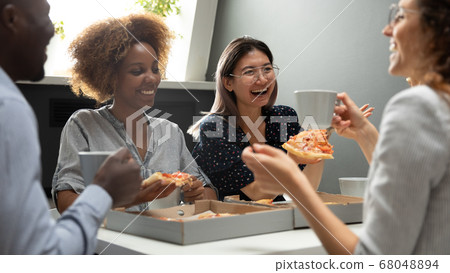 Joyful friendly multicultural team having fun eating pizza together Joyful friendly multicultural team having fun eating pizza together 68048894