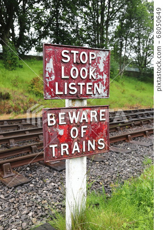 Stop Look Listen Railway Sign.  A sign warning pedestrians to stop, look and listen and beware of oncoming trains before they cross the railway line. 68050649