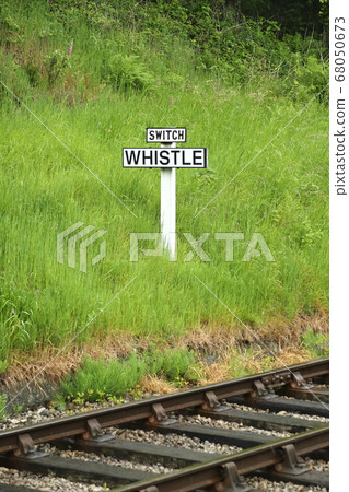 Whistle Railway Sign. The view across railway track towards a sign requiring oncoming trains to blow their whistle. Whistle Railway Sign. The view across railway track towards a sign requiring oncoming trains to blow their whistle. 68050673