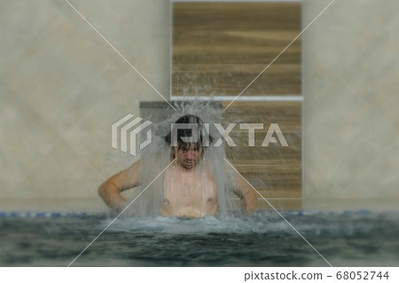 Young man enjoying pool spa day in relaxing vacation resort. Hydro massage for neck pain.Relaxing under water jet,neck and spine massage. Young man enjoying pool spa day in relaxing vacation resort. Hydro massage for neck pain.Relaxing under water jet,neck and spine massage. 68052744