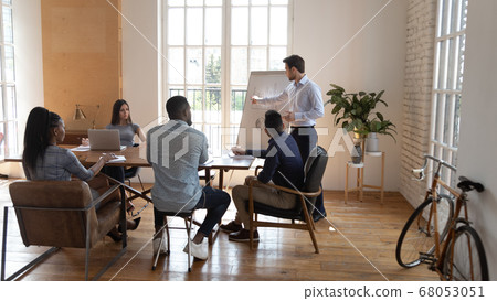 Businessman speaker giving presentation to multiracial business people in office Businessman speaker giving presentation to multiracial business people in office 68053051