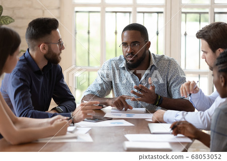 Serious male black executive talk to staff people at briefing Serious male black executive talk to staff people at briefing 68053052
