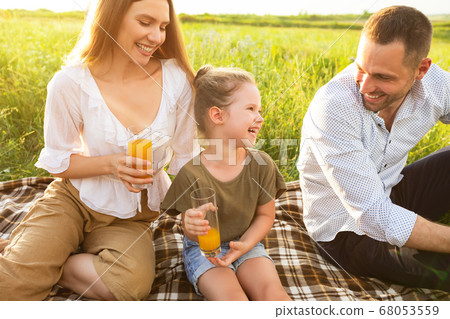 Laughing family drinking orange juice from glasses Laughing family drinking orange juice from glasses 68053559