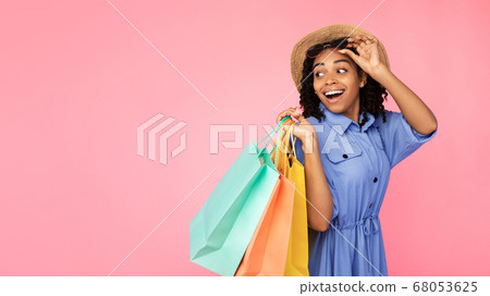 Excited African Girl Carrying Shopper Bags Looking Aside, Pink Background Excited African Girl Carrying Shopper Bags Looking Aside, Pink Background 68053625