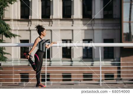 Sports in city at summer. African american girl doing exercises for legs Sports in city at summer. African american girl doing exercises for legs 68054000