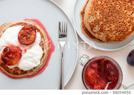 Banana pancakes or crumpets with plums and sour cream. Banana pancakes or crumpets with plums and sour cream. 68054050