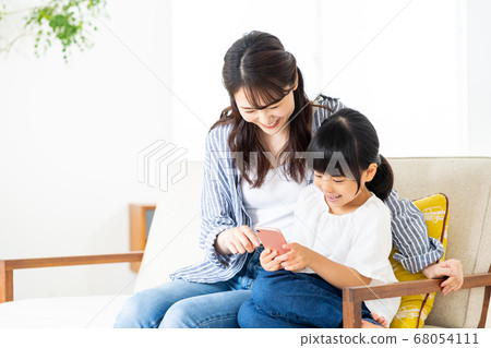 Parent and child (mother and child) relaxing together on a smartphone 68054111