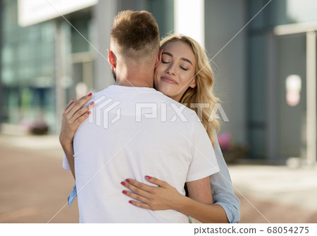 Man picking up his wife near the airport building Man picking up his wife near the airport building 68054275