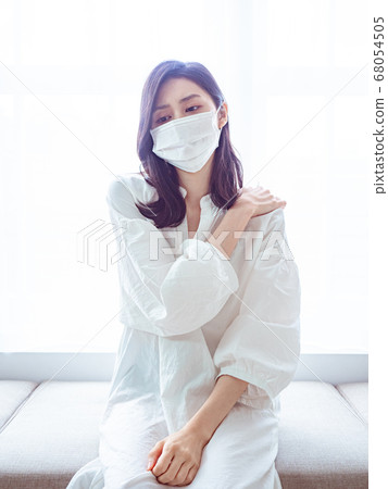 Young asian woman wearing surgical mask and suffering from pain in shoulder Young asian woman wearing surgical mask and suffering from pain in shoulder 68054505