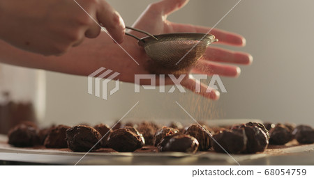 young woman sprinkle cocoa powder on chocolate truffles young woman sprinkle cocoa powder on chocolate truffles 68054759