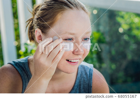 Portrait of Beauty Red-haired woman with eye patches showing an effect of perfect skin. Spa Girl 68055167