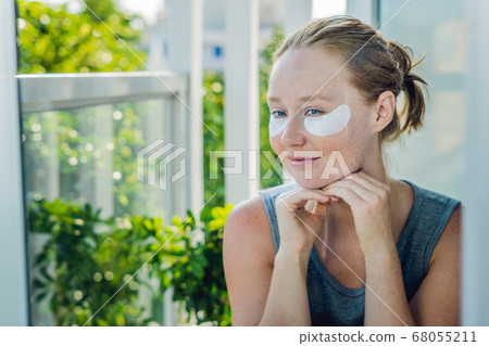 Portrait of Beauty Red-haired woman with eye patches showing an effect of perfect skin. Spa Girl 68055211