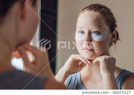 Portrait of Beauty Red-haired woman with eye patches showing an effect of perfect skin. Spa Girl 68055227