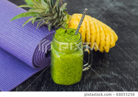 Green smoothies made of spinach and pineapple and a yoga mat. Healthy eating and sports concept 68055256