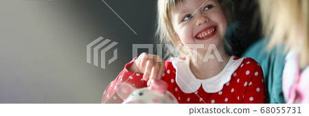Happy little girl in red dress hold silver coin in hand Happy little girl in red dress hold silver coin in hand 68055731