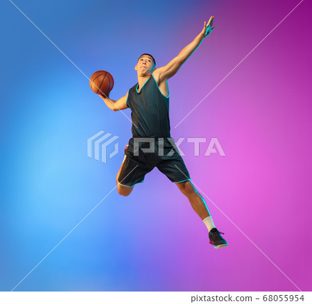 Young basketball player in motion on gradient studio background in neon light 68055954