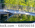 in a city park a metal bridge over a river at dawn. 68056038