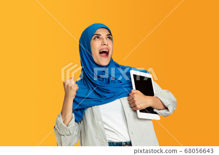 Portrait of young muslim woman isolated on yellow studio background 68056643