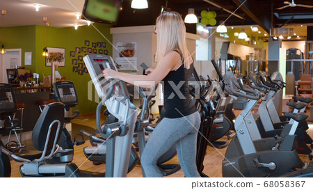 Young and sexy girl is running on a stepper at the gym 68058367