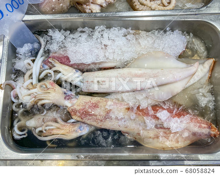 Frozen uncooked squids on ice for sale at seafood market Frozen uncooked squids on ice for sale at seafood market 68058824