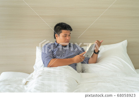 Businessman relaxing by reading book before bed time 68058923