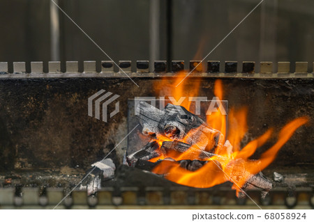 Hot flaming fire on charcoal grilling machine in restaurant Hot flaming fire on charcoal grilling machine in restaurant 68058924