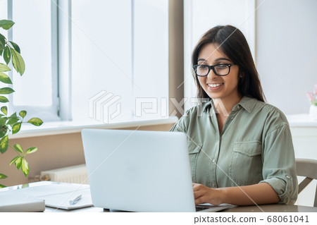 Happy indian young woman using laptop computer work study at home office. 68061041