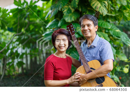 Middle aged couple playing guitar while relax Middle aged couple playing guitar while relax 68064308