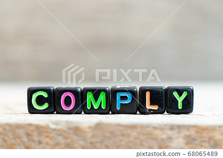Black bead with color letter in word comply on wood background 68065489