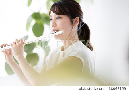 Young woman playing flute 68068169