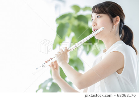 Young woman playing flute 68068170