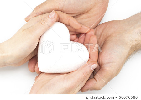 Man and woman holding a white heart in hands Man and woman holding a white heart in hands 68076586