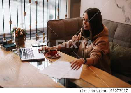 Attractive young businesswoman is typing on laptop computer and working with paper document. 68077417
