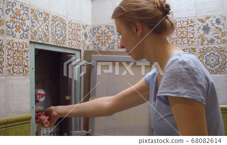 Woman shuts off water in an apartment Woman shuts off water in an apartment 68082614