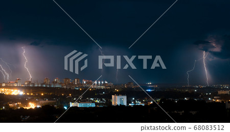 Several bright lightning bolts strike the ground in the city 68083512
