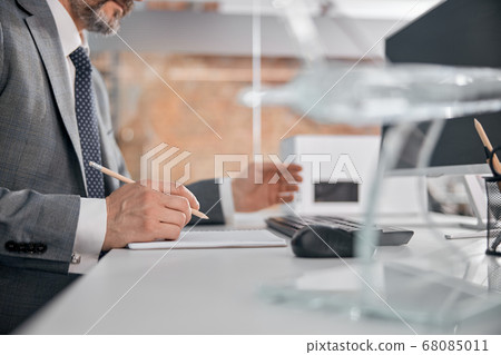 Male worker writing in spiral notebook in office Male worker writing in spiral notebook in office 68085011