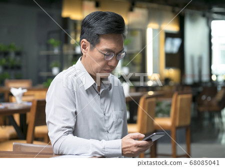 Chinese businessman looking at his cellphone in Chinese businessman looking at his cellphone in 68085041