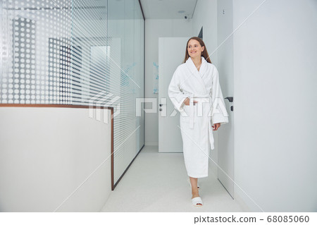 Smiling cheerful female in the white dressing gown going to the beauty procedure Smiling cheerful female in the white dressing gown going to the beauty procedure 68085060