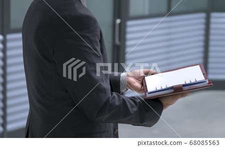 Businessman holding and open up diary or planner Businessman holding and open up diary or planner 68085563