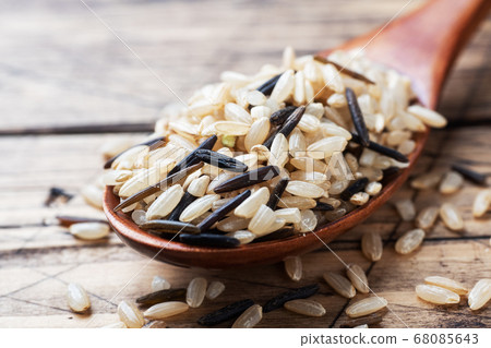 Raw wild rice in a wooden spoon. Raw rice grits on a wooden background. Copy space. Raw wild rice in a wooden spoon. Raw rice grits on a wooden background. Copy space. 68085643