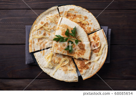 Pieces of quesadilla with mushrooms sour cream and cheese on a plate with parsley leaves. Wooden background copy space. Pieces of quesadilla with mushrooms sour cream and cheese on a plate with parsley leaves. Wooden background copy space. 68085654