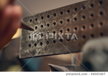 Experienced jeweler reducing thickness of metal wire Experienced jeweler reducing thickness of metal wire 68085867