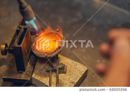 Jeweler melting the metal placed in a crucible Jeweler melting the metal placed in a crucible 68085896