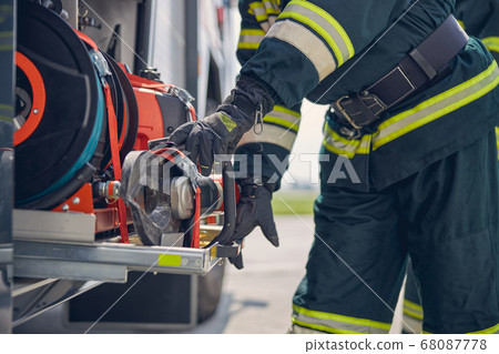 Portrait of firefighter wearing protective gloves working on fire engine Portrait of firefighter wearing protective gloves working on fire engine 68087778