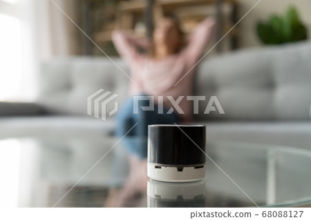 Portable wireless speaker on table with woman relaxing at home Portable wireless speaker on table with woman relaxing at home 68088127