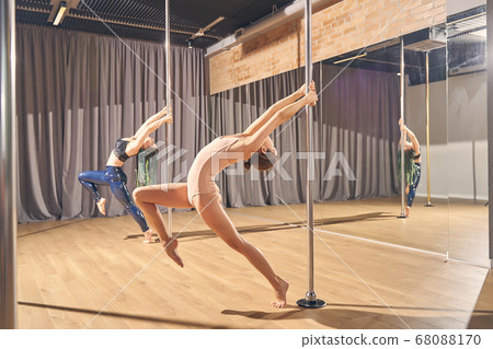 Skillful female dancers doing acrobatic tricks on pylons 68088170
